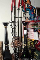 Various tall black metal candle holders with gold accents and twisted detailing, some standing on the floor