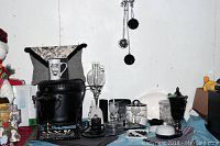 Wide view of the lot showing black ornate footstool, white ceramic items, glass decanter, black and white cookie jar, placemats and assorted black and white decor pieces on table.