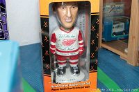 Bobble head doll of Gordie Howe in original display box with orange and black colors, showing full figure in hockey uniform.