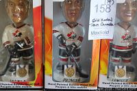Close-up of three hand painted hockey bobblehead dolls in original packaging, showing players Pronger, Lemieux, and Teniia with gold medal details on bases.