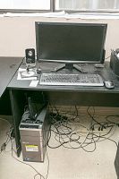 Full setup on desk showing monitor, keyboard, mouse, left speaker and tower under desk