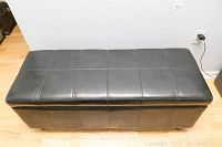Front view of black faux leather hall bench with stitched square pattern on top and sides.