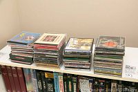 Wide shot showing approximately 50 CDs stacked in four piles on a table beside books.