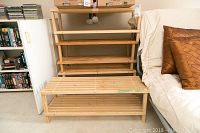 Four wooden shoe racks grouped together next to a couch showing size and condition with minor wear