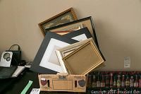 Photo showing multiple frames stacked against wall and a box with cardboard featuring various frame types for size comparison
