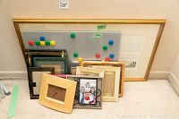 10 assorted picture frames, magnetic board with colored magnets, and large framed statistical report leaning on a wall