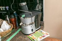 Photo of the full Jack LaLanne Power Juicer on a kitchen counter with a basket and other kitchen items in the background.
