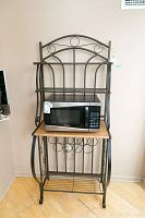 Full view of bakers rack showing metal frame, wooden middle shelf, bottom slatted metal shelf, and some scratches/spots on surfaces.