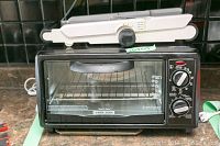 Black & Decker toaster oven showing front with wire rack and missing tray visible inside, two control knobs on side