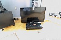 Emerson 32 inch TV with Samsung DVD VCR combo player below on the floor with attached RCA cables.