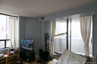 Curtain panels hung on windows in a living room setting, showing the space and light filtering through.