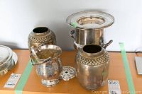 Full view of wine bucket, two vases, and strainer/coaster on wood shelf