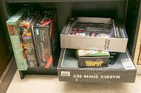 Photo showing variety of boxed games and tool kit on shelf