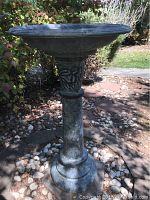 Full side view of the gray resin bird bath showing textured stone-like surface, decorative column, and wide shallow basin at the top.