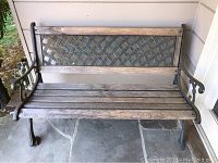 Front view of outdoor bench showing wood slatted seat, metal backrest with diamond pattern, and wood top rail.