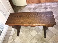 Top view of carved wood bench showing grain and carving detail.