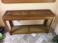 Top and side view of wooden entry console table with wood grain top and woven cane shelf below.