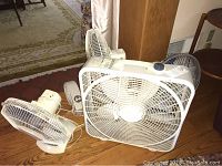 Photo showing all five fans placed on wooden floor with various sizes and types visible.