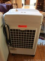 Full view of white rectangular portable cooler showing vent and power cord wrapped on side.