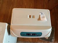 Top and front view of white Cool Air 3000 portable swamp cooler with teal blue control panel and MaxSold auction sticker attached on top.