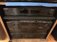 Front view of Sony sound system components stacked: amplifier on top, tuner in the middle, equalizer on bottom, all black finish with labeled controls.