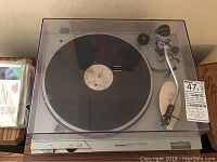 Technics SL-D1 turntable with closed dust cover on top of its base and vinyl record on platter