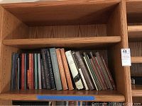 Books arranged on a wooden shelf with visible spines showing titles related to music.