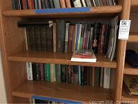Wooden bookshelf with three shelves filled with various books including larger volumes and assorted historical and musical themed titles.