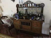 Front view of the wooden buffet showing decorative tiled backsplash, multiple drawers, and cabinet doors with spindle detail at center.