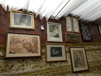 Seven framed wall art pieces hanging on a wall above patterned sofa.