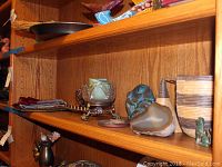 Shelf with a large geode, ceramic or pottery items, and other small decorative pieces