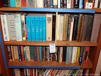 Photo of books on wooden shelves featuring titles on Judaism, Jewish history, culture, and related topics including a set of blue hardcover volumes and others.
