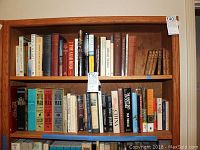 Wide view of two wooden bookshelves filled with a variety of history, religion, and cultural books, mainly hardcover editions.