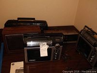 Five radios arranged on a wooden surface showing various sizes and designs, highlighting aged condition and original features