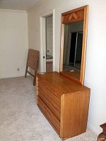 Wooden dresser with mirror on top, showing dresser drawers and mirror frame design.