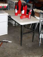 Rectangular folding table with fire extinguishers placed on top, viewed from the side in garage space.